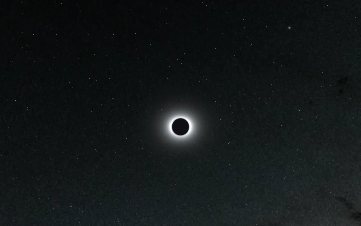 The Sun in total eclipse, a black disc ringed by the white corona, in a star-filled sky simulated over Zaragoza on August 12, 2026